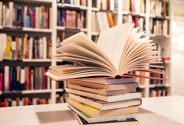 numérique responsable et référencement. Photo d'une pile de livres devant la bibliothèque d'une librairie pour illustrer le référencement naturel SEO et le référencement payant SEA.